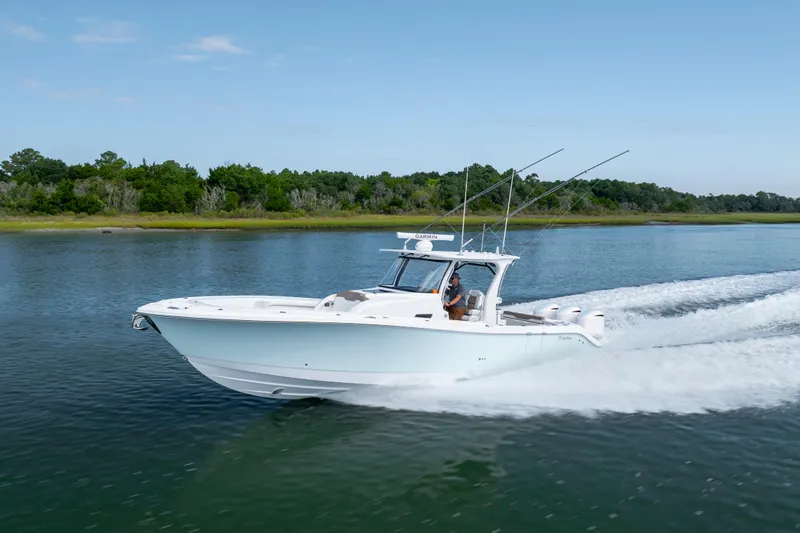  Yacht Photos Pics 2021 Edgewater 370CC boat cruising on a calm lake with lush green shoreline.