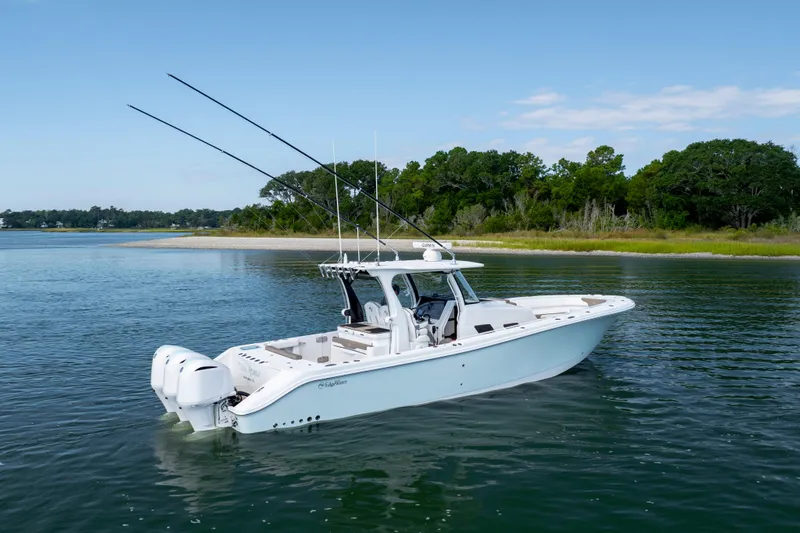  Yacht Photos Pics 2021 Edgewater 370CC boat on calm water near a lush shoreline.