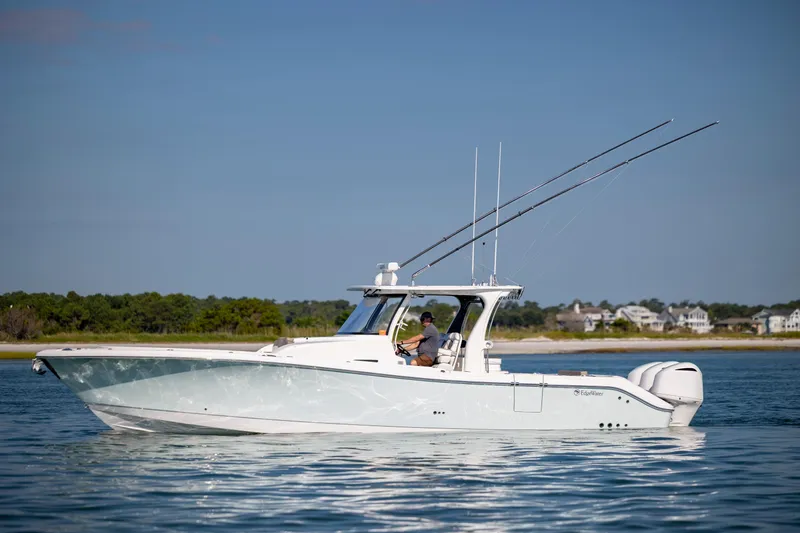  Yacht Photos Pics 2021 Edgewater 370CC boat on calm water, featuring fishing rods and scenic shoreline.