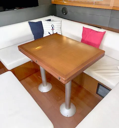 Journey Yacht Photos Pics Interior of 2019 Beneteau Oceanis 48 with wooden table and cushioned seating.