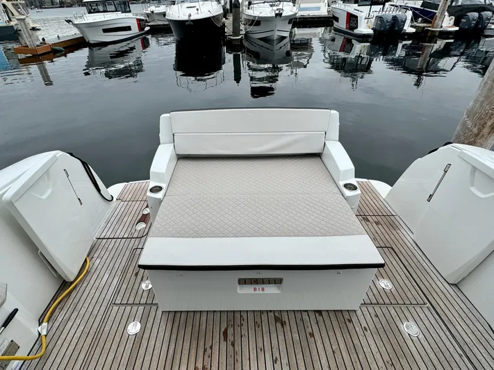 September II Yacht Photos Pics 2018 Jeanneau NC 11 boat with cushioned seating at the stern, docked at a marina.