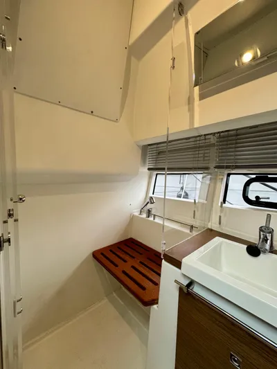 September II Yacht Photos Pics 2018 Jeanneau NC 11 bathroom with sink, wooden bench, and window blinds.