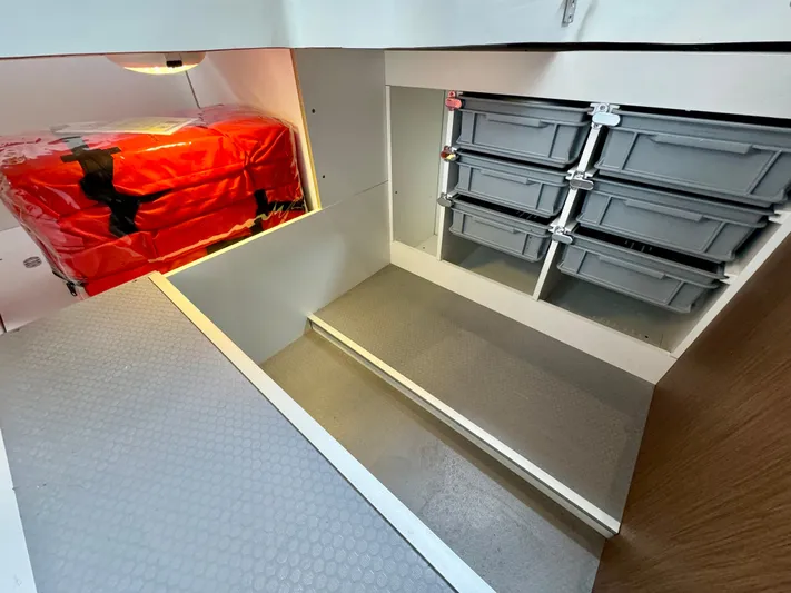 September II Yacht Photos Pics 2018 Jeanneau NC 11 storage compartment with red safety equipment and gray storage bins.