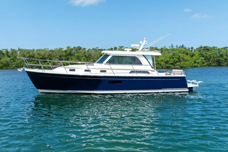 Five O'clock Yacht Photos Pics 2013 Sabre 38 Salon Express yacht on calm water, surrounded by lush greenery.