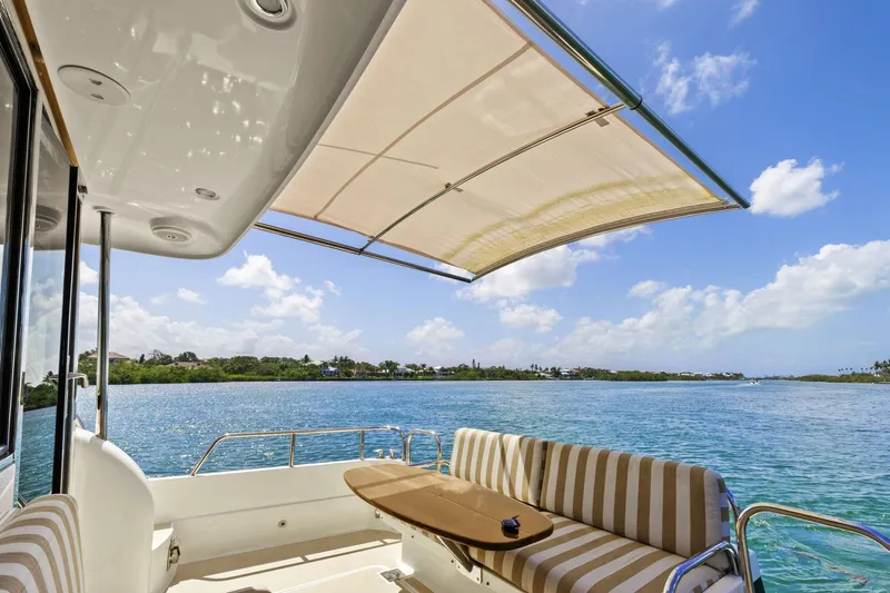 Five O'clock Yacht Photos Pics 2013 Sabre 38 Salon Express yacht with striped seating, scenic water view, and retractable canopy.