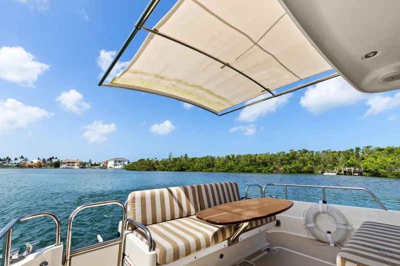 Five O'clock Yacht Photos Pics 2013 Sabre 38 Salon Express yacht with striped seating, canopy, and scenic waterfront view.