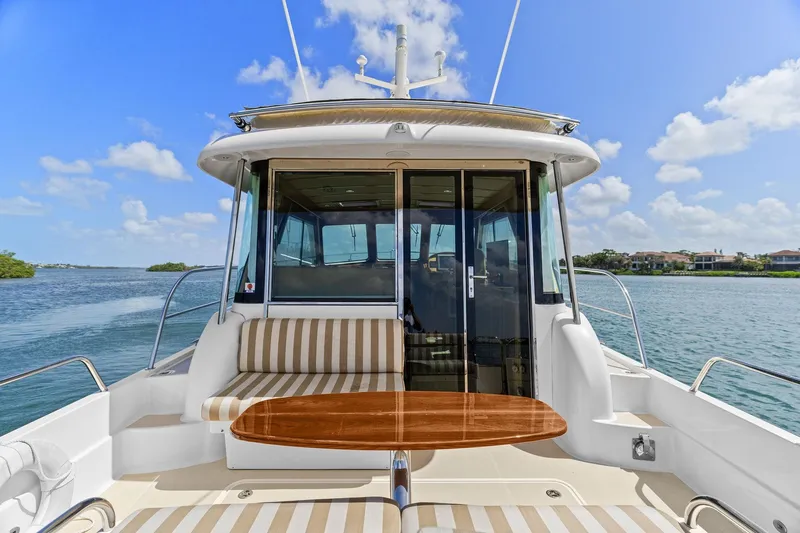 Five O'clock Yacht Photos Pics 2013 Sabre 38 Salon Express yacht with striped seating and wooden table on deck.