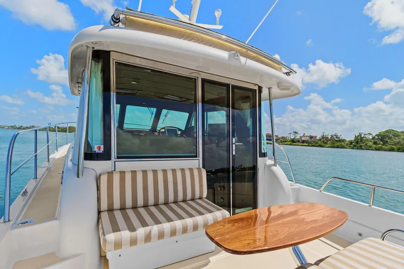 Five O'clock Yacht Photos Pics 2013 Sabre 38 Salon Express yacht with striped seating and wooden table on deck.