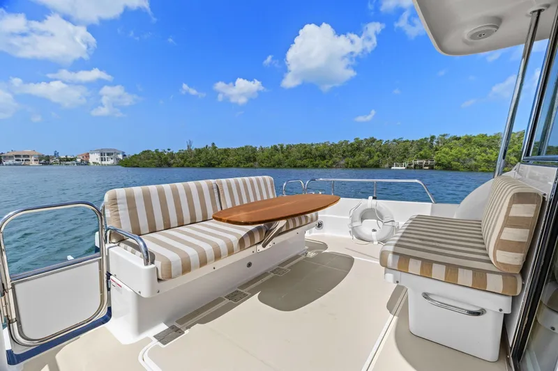 Five O'clock Yacht Photos Pics 2013 Sabre 38 Salon Express yacht deck with striped seating and wooden table, scenic water view.