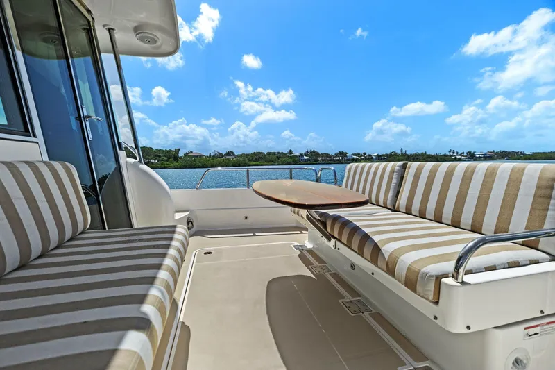 Five O'clock Yacht Photos Pics 2013 Sabre 38 Salon Express yacht with striped seating, table, and scenic water view.