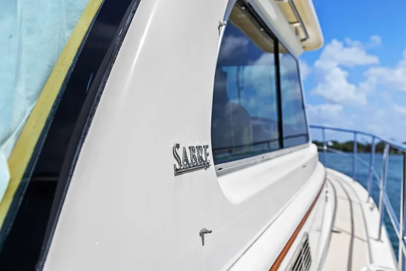 Five O'clock Yacht Photos Pics 2013 Sabre 38 Salon Express yacht, side view with logo, against blue sky and water.