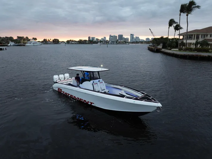 Heavy Metal Yacht Photos Pics Statement 380 Open 2017 boat cruising on a calm waterway at sunset, city skyline in background.