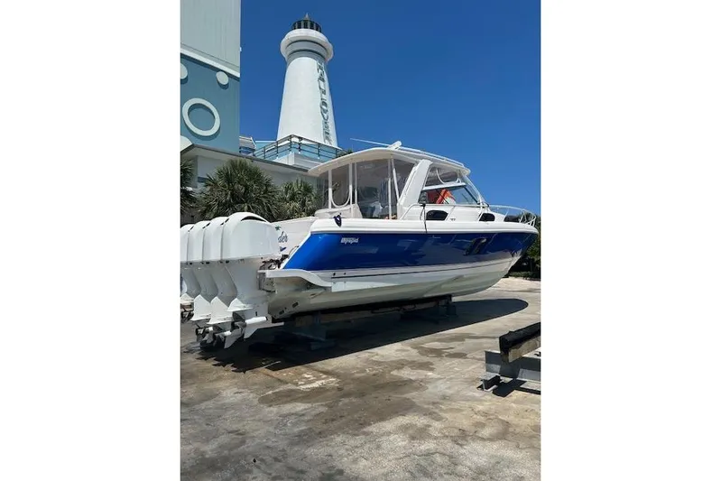  Yacht Photos Pics 2017 Intrepid 475 Sport Yacht with blue hull, docked near a lighthouse.