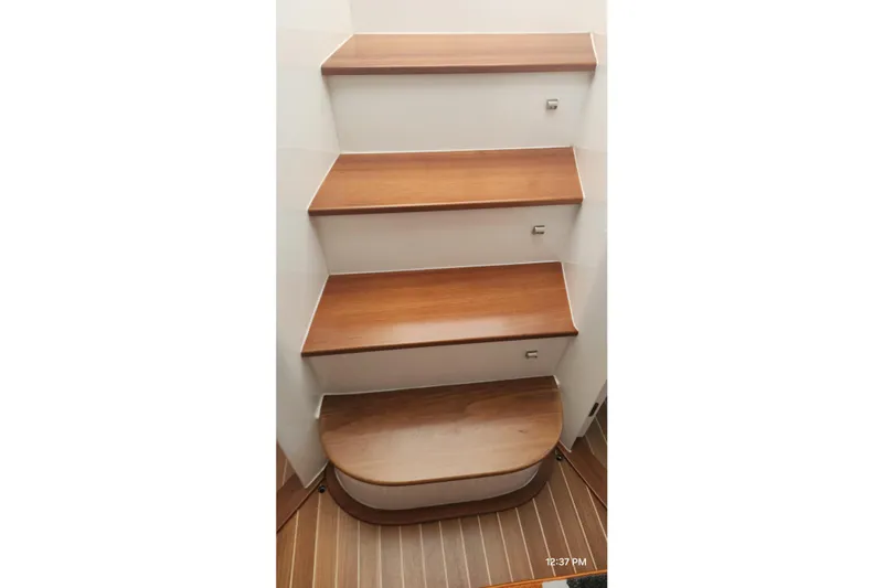  Yacht Photos Pics Wooden steps inside a 2017 Intrepid 475 Sport Yacht, showcasing elegant interior design.