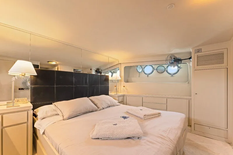 Daylami Yacht Photos Pics Luxurious bedroom interior on a 1972 Benetti Yachts Classic, featuring elegant decor and porthole windows.