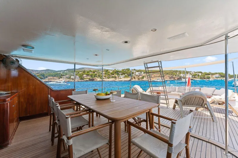 Daylami Yacht Photos Pics Luxurious 1972 Benetti Yachts Classic deck with dining area overlooking scenic coastal view.