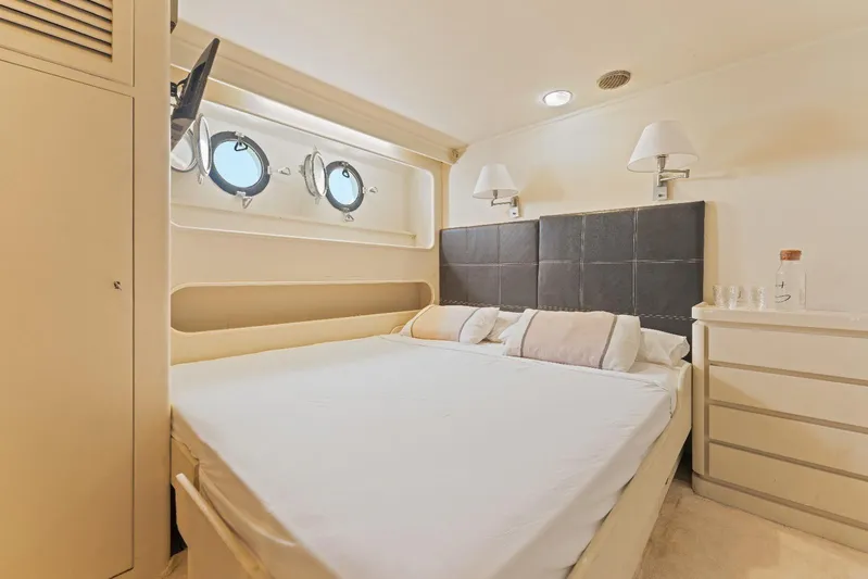 Daylami Yacht Photos Pics Luxurious bedroom interior on a 1972 Benetti Yachts Classic, featuring elegant decor and porthole windows.