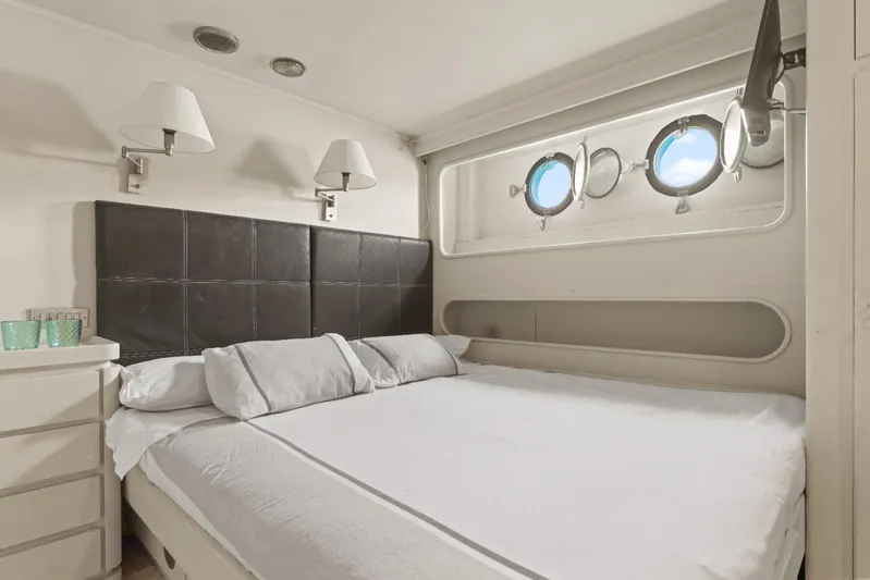 Daylami Yacht Photos Pics Luxurious bedroom interior on a 1972 Benetti Yachts Classic, featuring porthole windows.