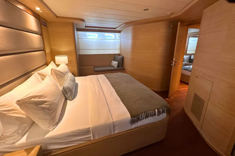 Celebrity Yacht Photos Pics Luxurious bedroom interior on 2001 Ses Yachts custom model, featuring elegant wood paneling and cozy bedding.