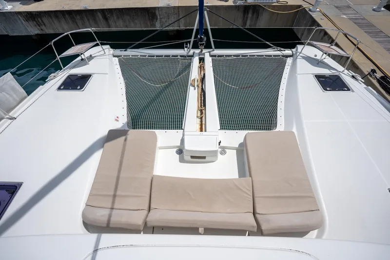 Starry Night Yacht Photos Pics 2022 Lagoon 46 catamaran deck with beige cushions and netting, docked at marina.