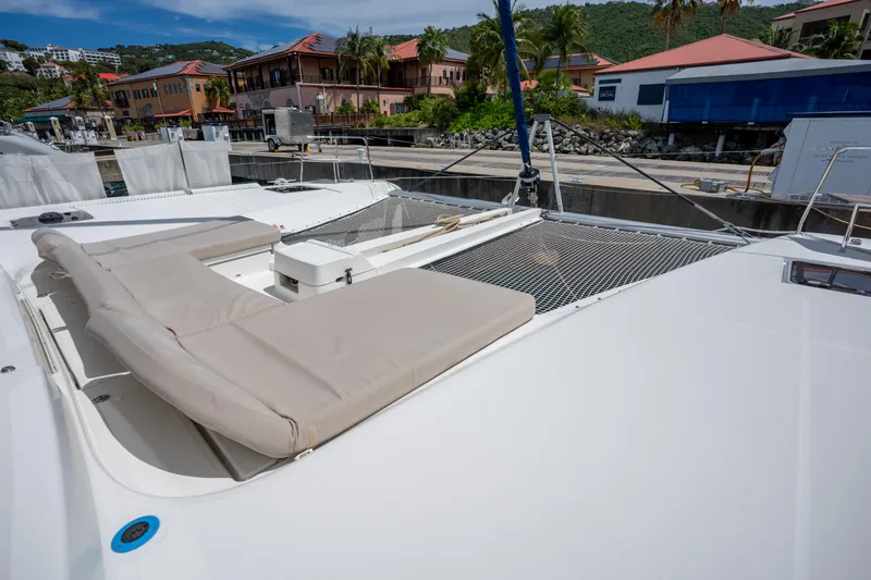 Starry Night Yacht Photos Pics 2022 Lagoon 46 catamaran with sunbathing area, docked in a scenic marina.