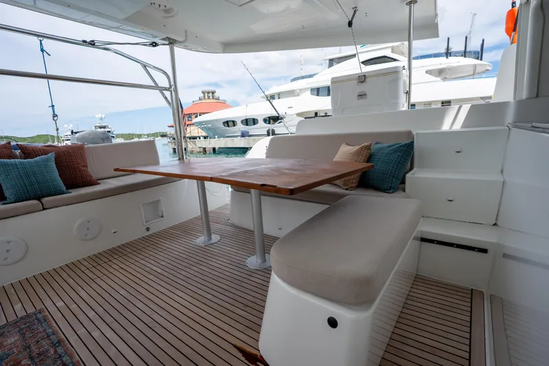 Starry Night Yacht Photos Pics 2022 Lagoon 46 yacht interior with seating and wooden table, docked at marina.