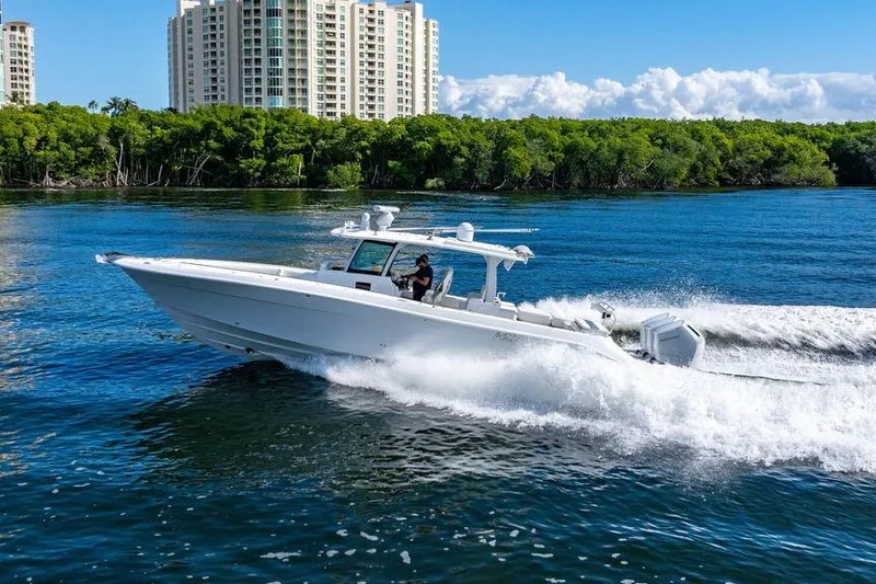  Yacht Photos Pics 2024 HCB 42 Lujo boat cruising on water near city skyline and lush greenery.