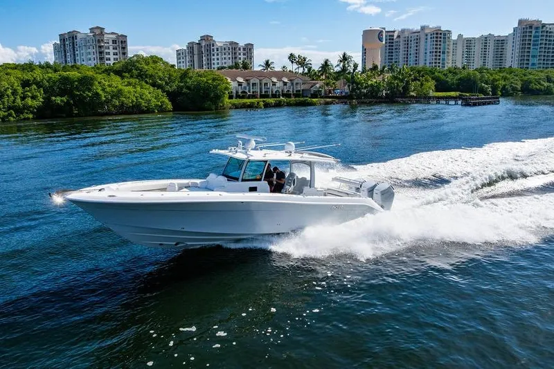  Yacht Photos Pics 2024 HCB 42 Lujo boat cruising on a scenic waterway with city skyline backdrop.