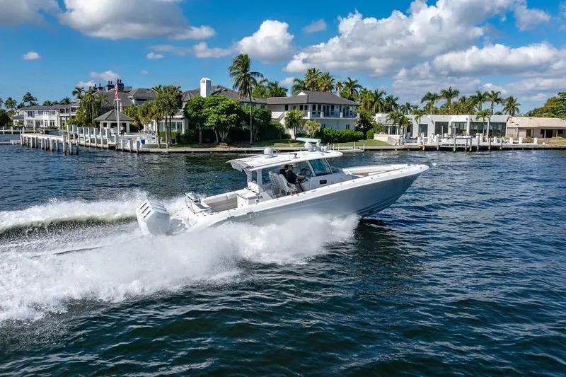  Yacht Photos Pics 2024 HCB 42 Lujo boat cruising on a sunny waterfront with palm trees.