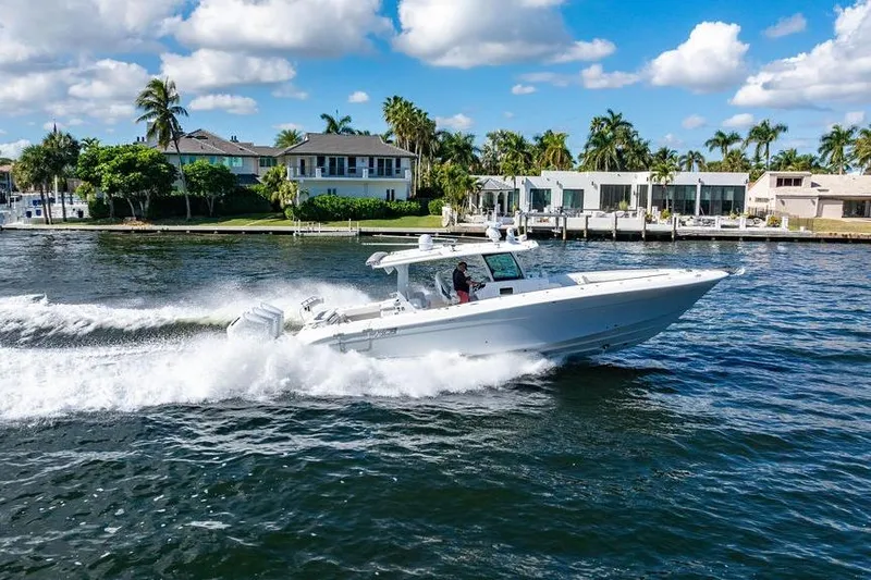  Yacht Photos Pics 2024 HCB 42 Lujo boat cruising on a sunny waterfront with luxury homes.