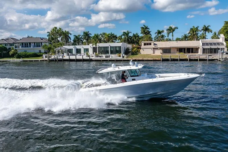  Yacht Photos Pics 2024 HCB 42 Lujo boat cruising on a sunny waterfront with modern homes.