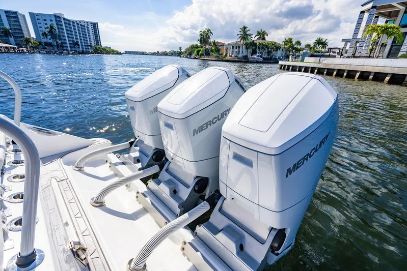  Yacht Photos Pics 2024 HCB 42 Lujo boat with triple Mercury outboard engines on a sunny waterfront.