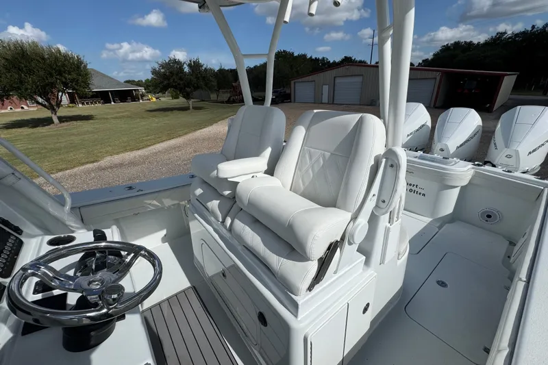  Yacht Photos Pics 2020 Yellowfin 36 Offshore boat interior with white seating and steering wheel, parked outdoors.
