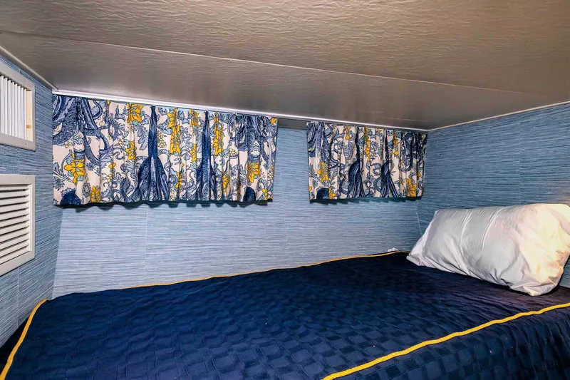 Freedom Yacht Photos Pics Cozy cabin bed with blue quilt and patterned curtains on a 1979 Burger Raised Pilothouse yacht.