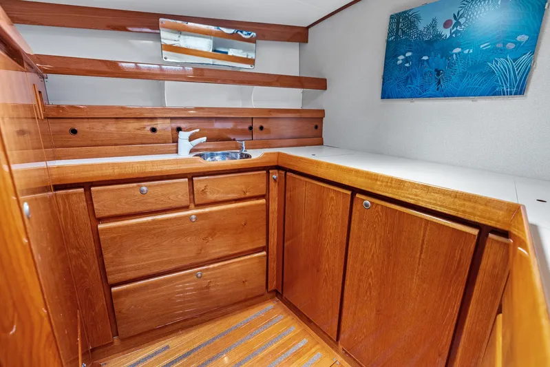 Godspeed Yacht Photos Pics Luxurious wooden yacht interior with cabinets, sink, and ocean-themed artwork, Custom Kelly Archer 1998.