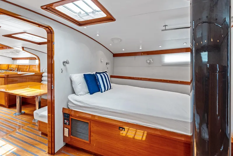Godspeed Yacht Photos Pics Luxurious yacht interior with wooden finishes, featuring a cozy bed and dining area.