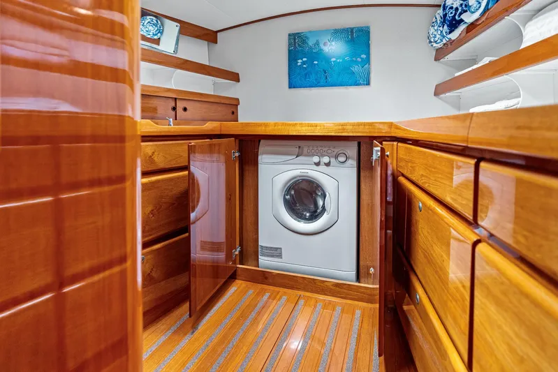 Godspeed Yacht Photos Pics Laundry area on a 1998 Custom Kelly Archer yacht with wooden cabinetry and washing machine.