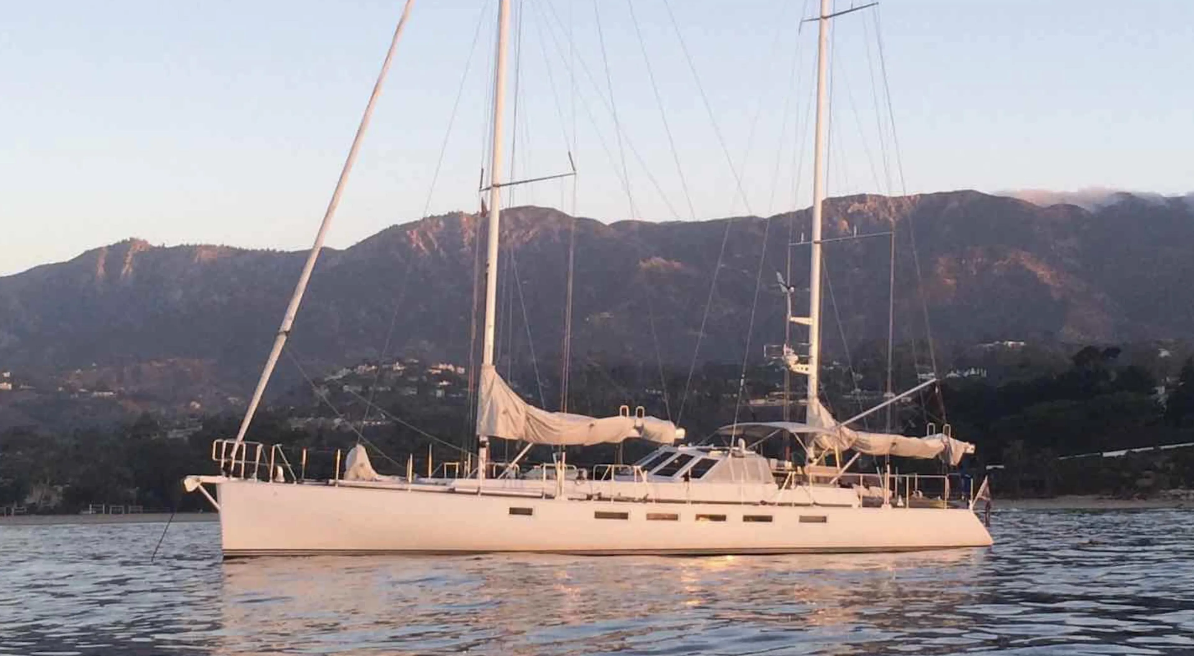 Sailing yacht "Kelly Archer" 1998 on calm waters with mountainous backdrop.