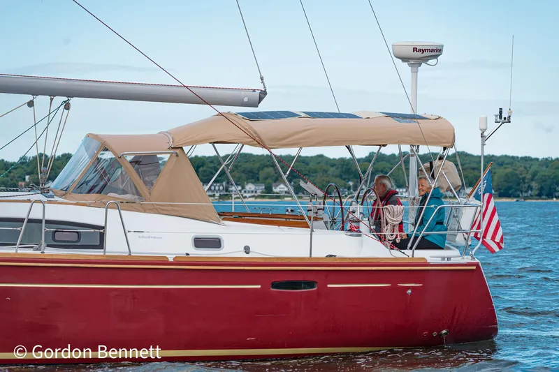 Queens Share Yacht Photos Pics 2008 Beneteau Oceanis 43 sailboat with red hull, cruising on a calm lake.