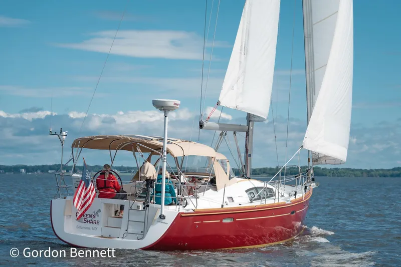 Queens Share Yacht Photos Pics 2008 Beneteau Oceanis 43 sailboat with red hull sailing on a sunny day.