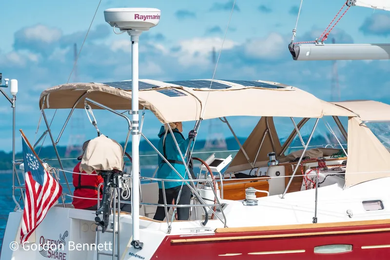 Queens Share Yacht Photos Pics 2008 Beneteau Oceanis 43 sailboat with beige canopy and American flag on open water.