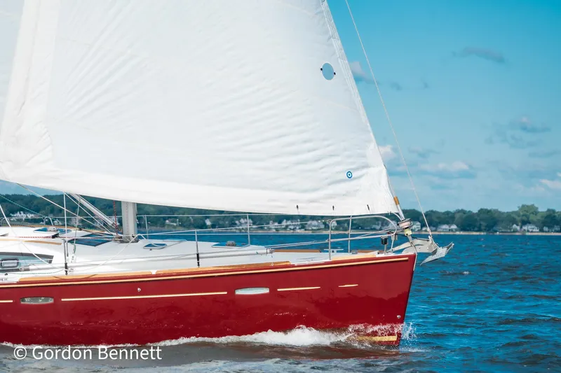 Queens Share Yacht Photos Pics 2008 Beneteau Oceanis 43 sailboat with red hull sailing on a sunny day.