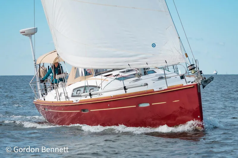 Queens Share Yacht Photos Pics 2008 Beneteau Oceanis 43 sailboat with red hull sailing on open water.