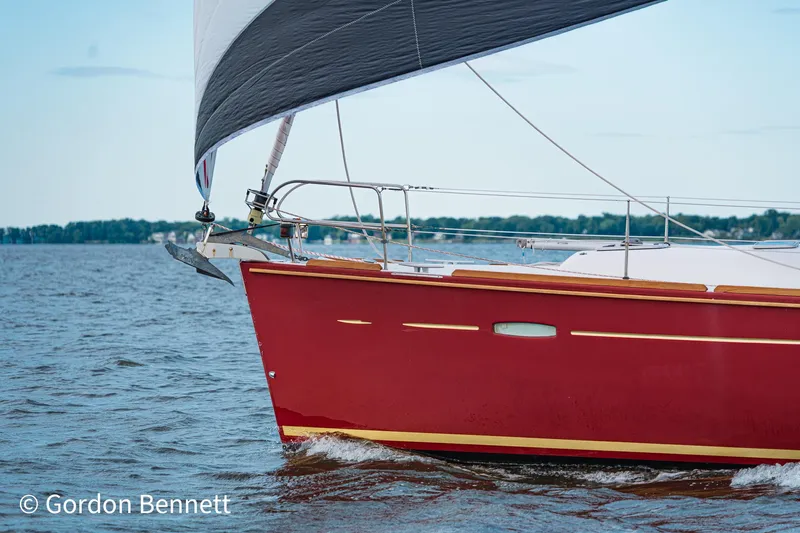 Queens Share Yacht Photos Pics Red Beneteau Oceanis 43 sailboat from 2008 sailing on a calm lake.