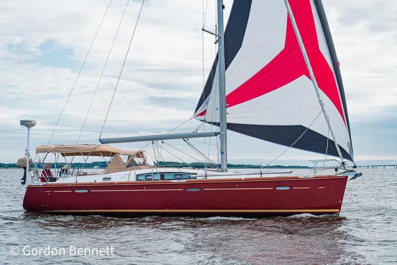 Queens Share Yacht Photos Pics 2008 Beneteau Oceanis 43 sailboat with red hull and colorful sails on open water.