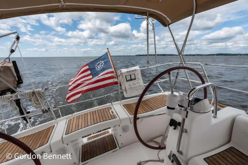 Queens Share Yacht Photos Pics Cockpit view of 2008 Beneteau Oceanis 43 sailboat with American flag on open water.