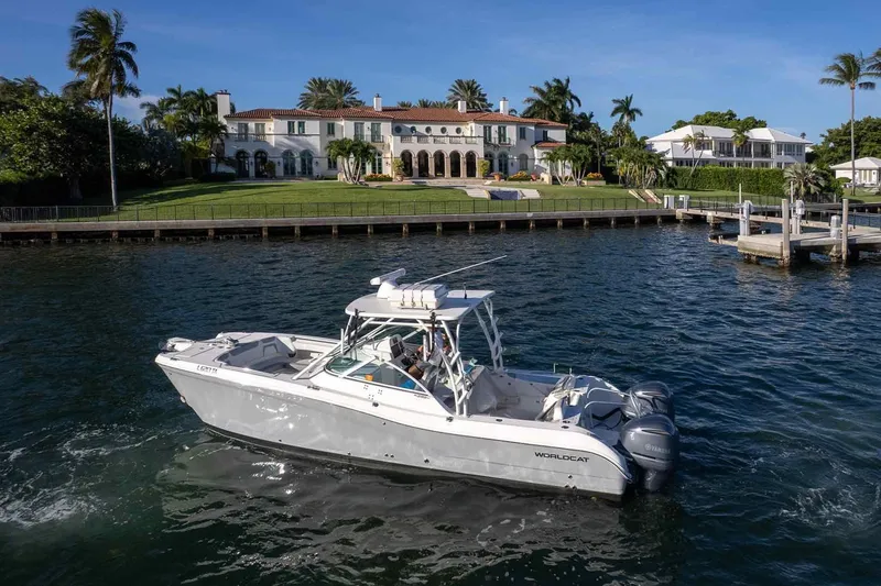  Yacht Photos Pics 2017 World Cat 295 DC boat cruising near a luxurious waterfront mansion.