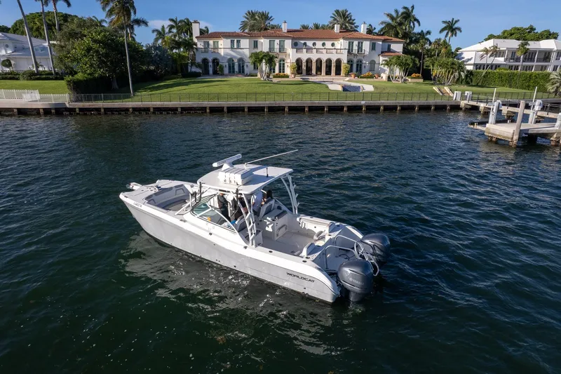  Yacht Photos Pics 2017 World Cat 295 DC boat cruising near luxurious waterfront mansion.