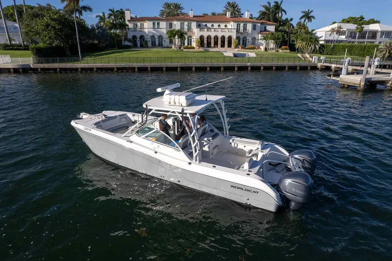  Yacht Photos Pics 2017 World Cat 295 DC boat cruising near luxurious waterfront mansion.