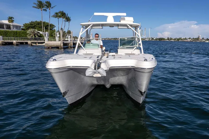  Yacht Photos Pics 2017 World Cat 295 DC boat on water, with clear blue sky and palm trees.